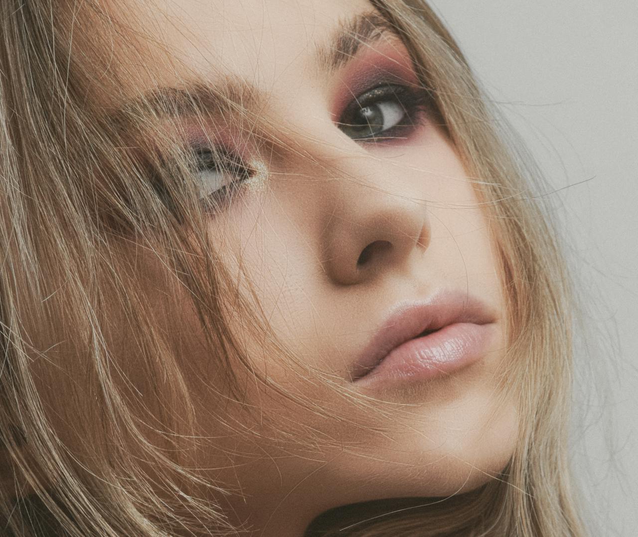 Close-up portrait of a woman with artistic makeup, enhancing natural beauty and elegance.
