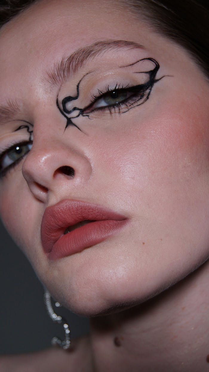 Elegant close-up of a woman with unique artistic eye makeup and red lipstick.