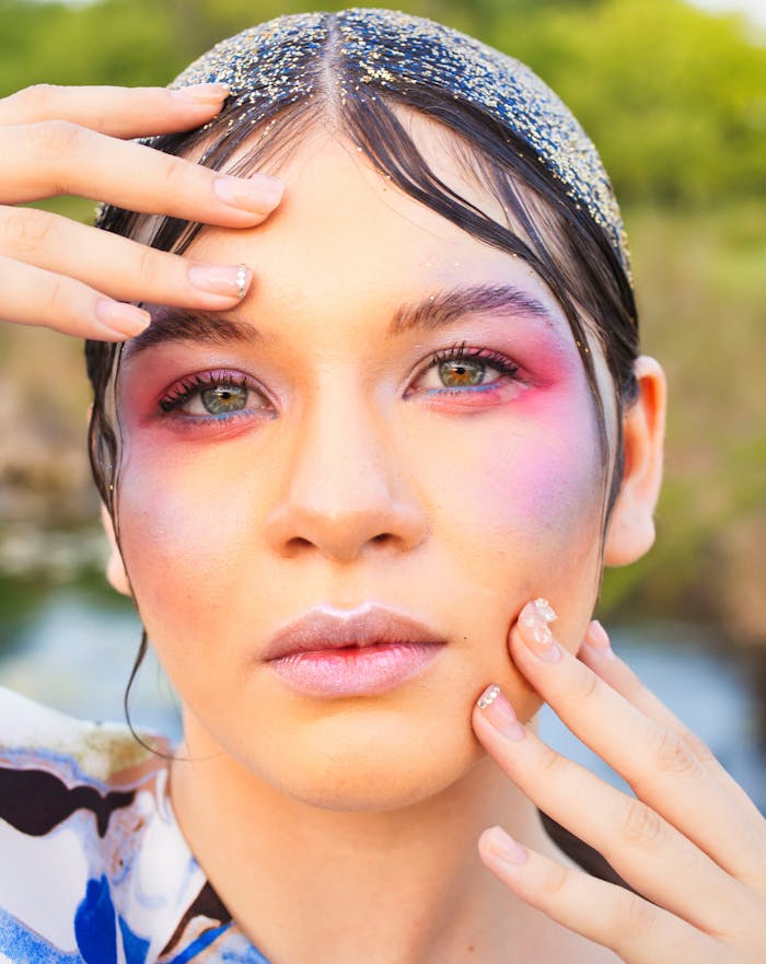 Creative portrait of a woman with vibrant makeup and glitter detail, emphasizing beauty and expression.