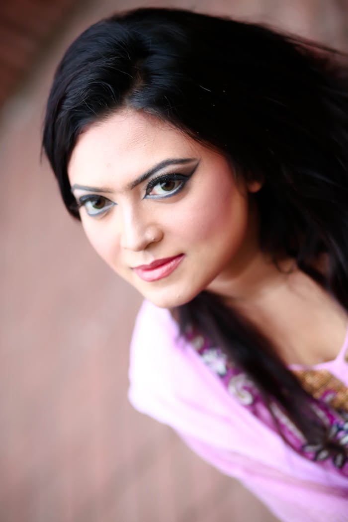 Services Artistic portrait of a young woman with dramatic eye makeup and long brunette hair.