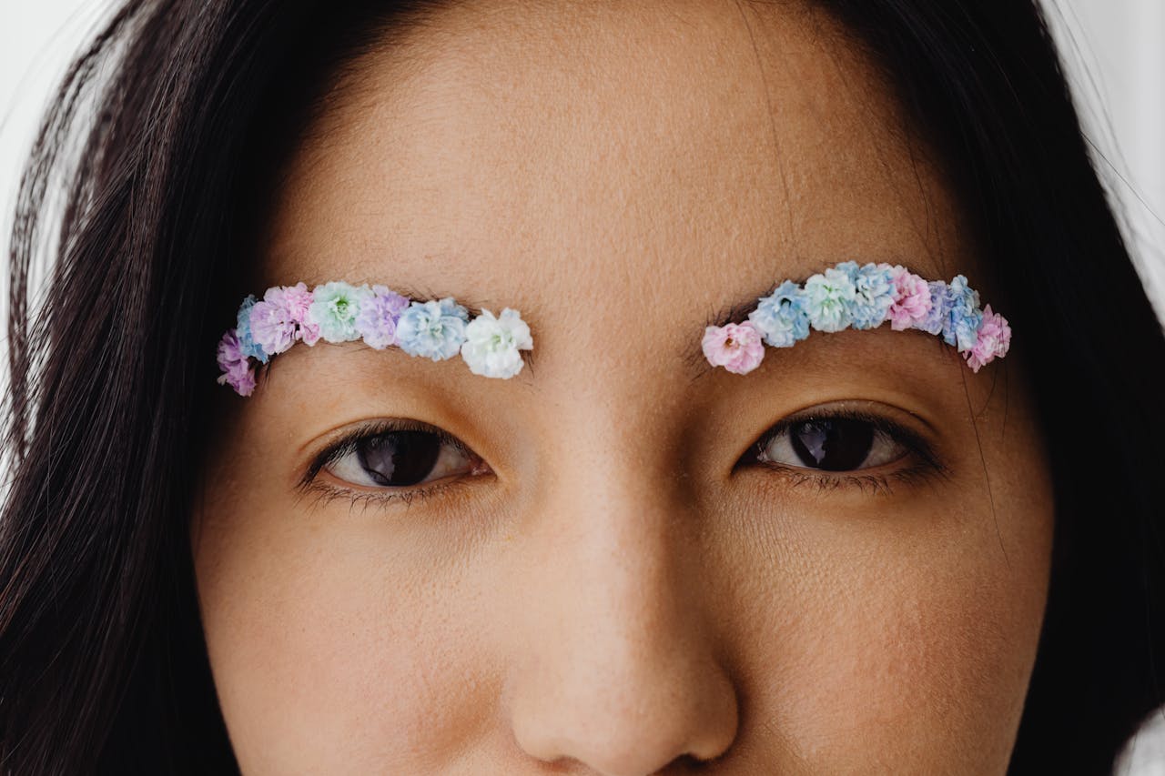 A close-up portrait of a woman with floral eyebrows, showcasing creative makeup art.