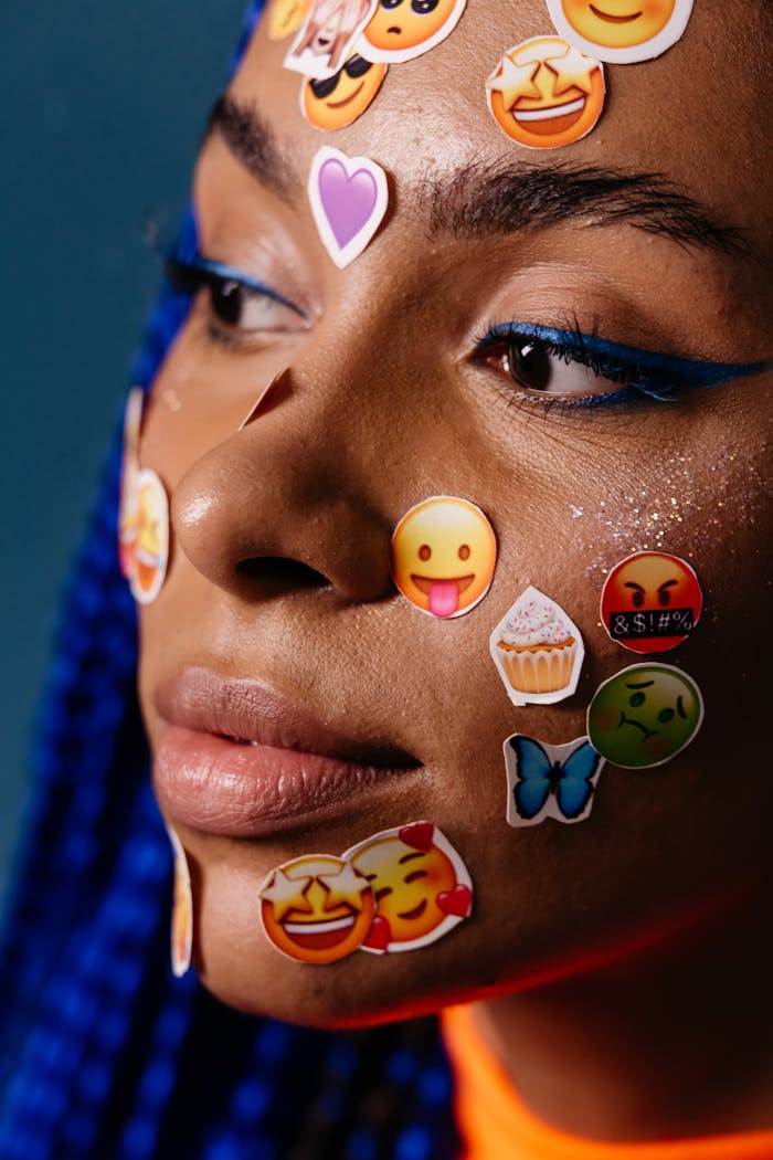 Close-up artistic portrait featuring colorful emoji stickers on a woman's face.